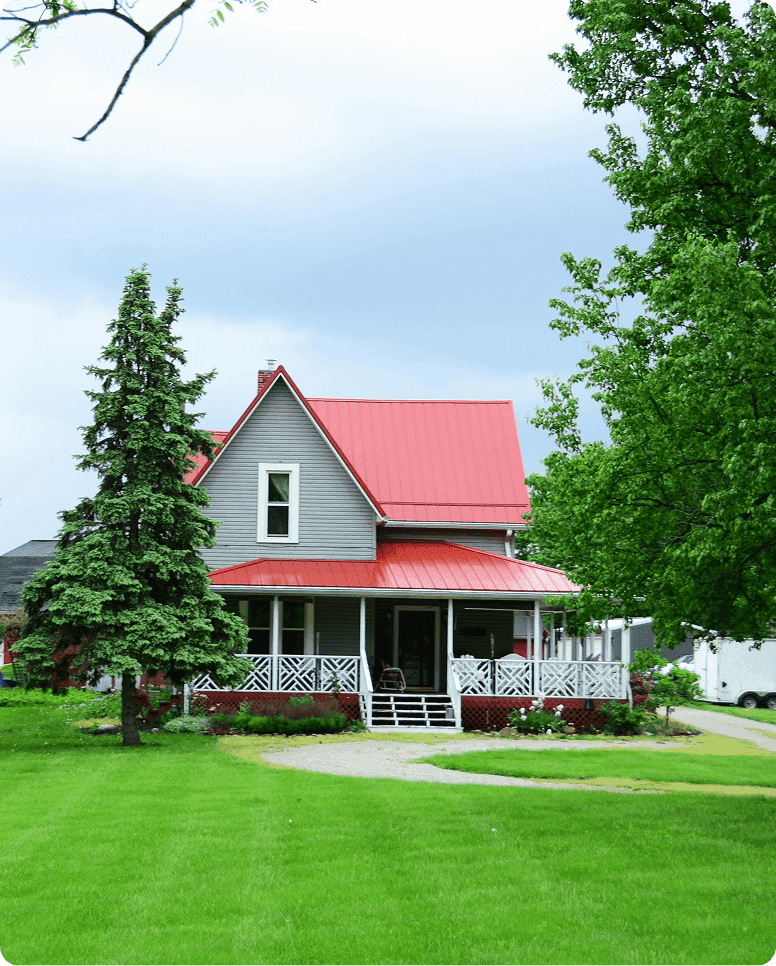 Farmhouse with a red metal roof and a manicured front lawn